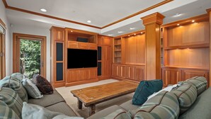 A spacious living room with a large flat-screen TV, built-in wooden cabinets, and a comfortable seating area. - Lake View home 4BR 5BA gym, game room, Large kitchen (Incline Village)