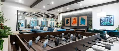 A modern indoor space with a foosball table, seating area, and artwork on the walls.