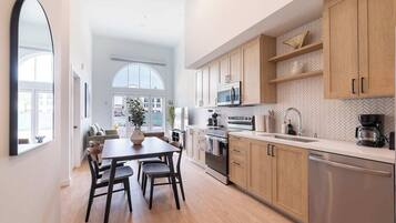 Una cocina moderna con armarios de madera, electrodomésticos de acero inoxidable y un amplio ventanal que proporciona luz natural.