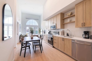 A modern kitchen with wooden cabinets, stainless steel appliances, and a large window providing natural light.