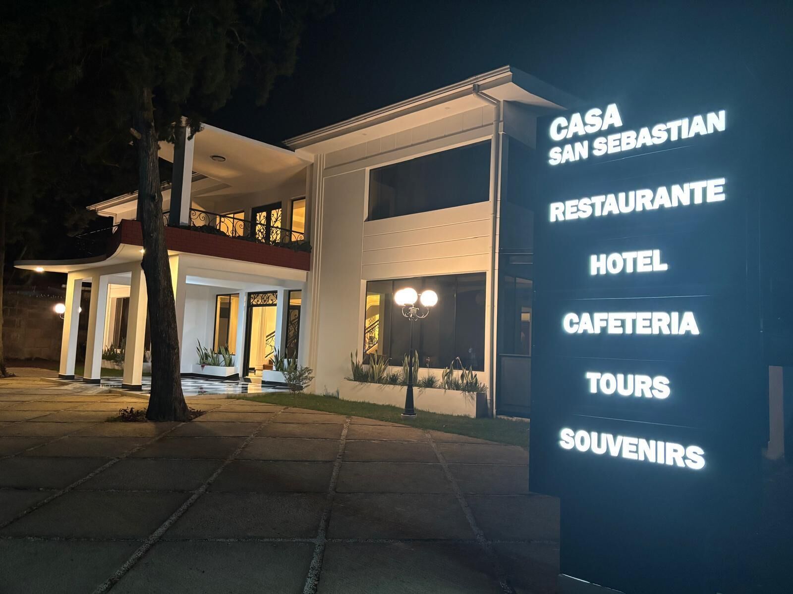 A modern building with a sign listing services such as a restaurant, hotel, and tours.