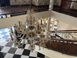 A grand chandelier with multiple arms and crystal decorations, suspended above a checkered floor. - Hotel San Sebastian (Diriamba)
