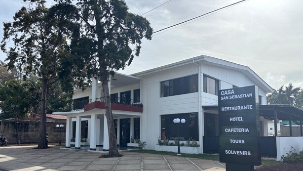 A modern building with a sign listing amenities including a restaurant, hotel, and tours.