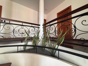 Una escalera curva con barandilla de metal y una jardinera con plantas verdes.