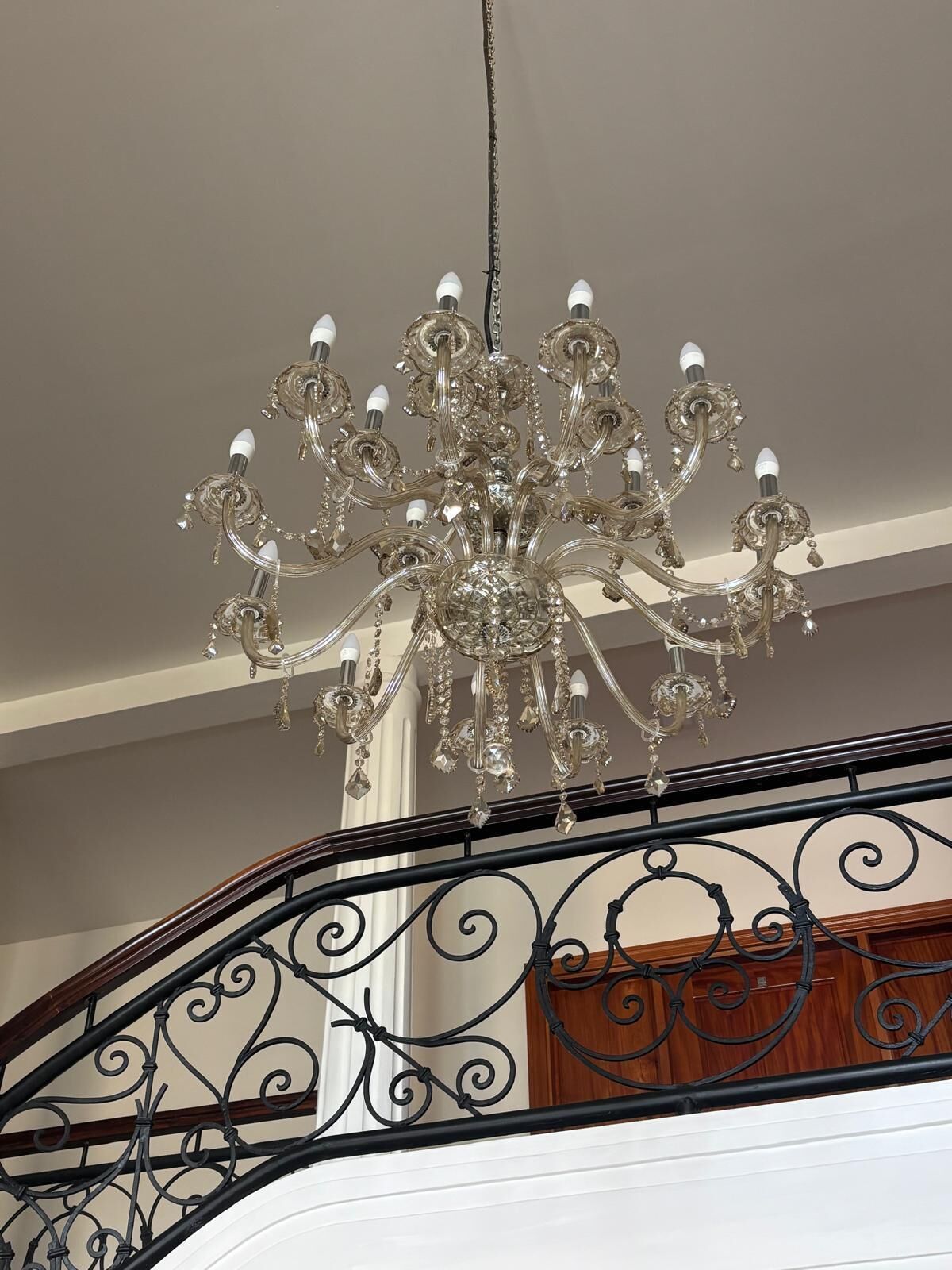 Un lustre à plusieurs bras, orné de décorations en cristal, suspendu au plafond.
