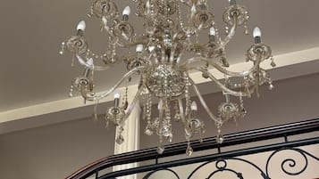 Un lustre à plusieurs bras, orné de décorations en cristal, suspendu au plafond.