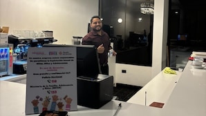 A hotel reception area with a modern chandelier, a coffee machine, and a sign about sexual exploitation prevention.