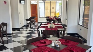 A dining area with checkered flooring, tables set with red napkins, and a ceiling fan.