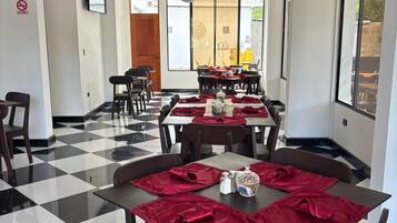 A dining area with checkered flooring, tables set with red napkins, and a ceiling fan.