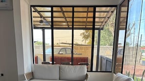 A modern interior with a checkered floor, a sofa, a coffee table, and a view of the outside through large windows.