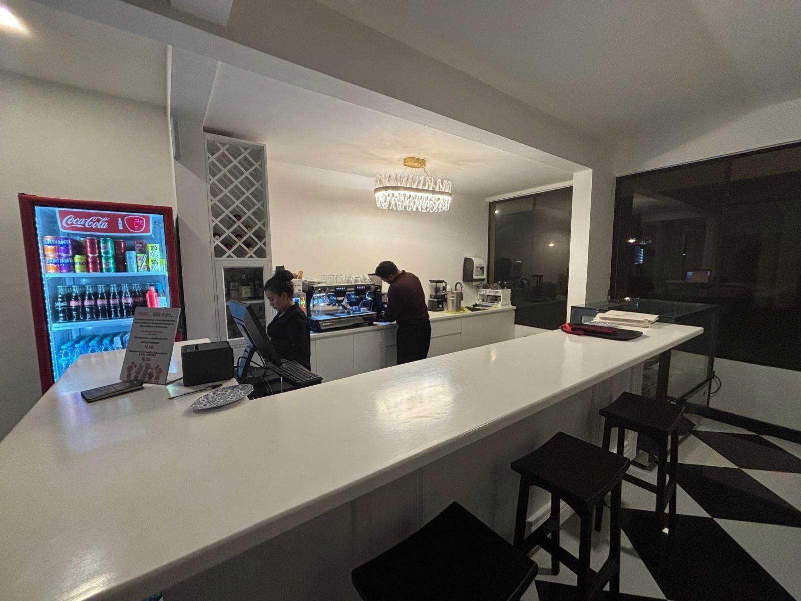 A bar area with a Coca-Cola refrigerator, a bar counter, and stools.