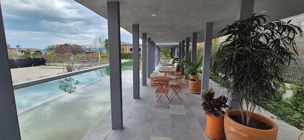 A covered outdoor area with a pool, seating, and potted plants.