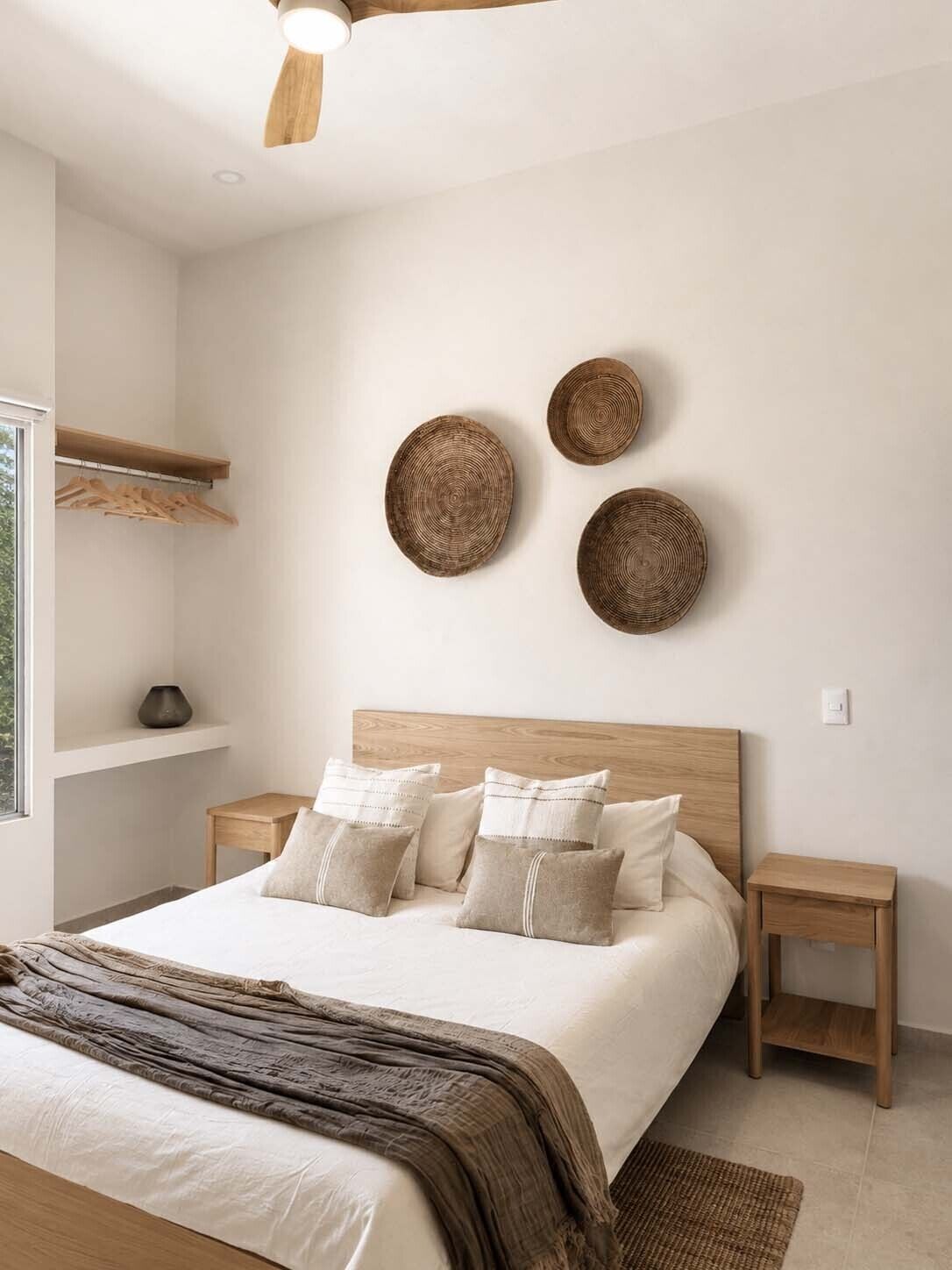 Une chambre moderne avec une tête de lit en bois, un grand lit agrémenté de nombreux coussins, des tables de chevet et des assiettes décoratives fixées au mur.