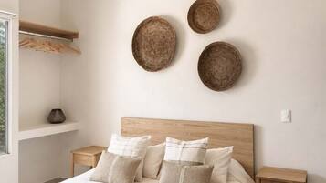 Une chambre moderne avec une tête de lit en bois, un grand lit agrémenté de nombreux coussins, des tables de chevet et des assiettes décoratives fixées au mur.