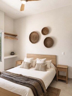Une chambre moderne avec une tête de lit en bois, un grand lit agrémenté de nombreux coussins, des tables de chevet et des assiettes décoratives fixées au mur.