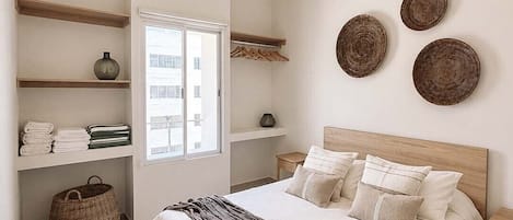 Une chambre à coucher comprenant un lit, un ventilateur de plafond, une fenêtre et des éléments de décoration fixés au mur.