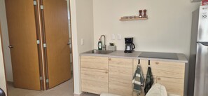 Une cuisine équipée d’un réfrigérateur en acier inoxydable, d’une machine à café et d’un meuble en bois avec un évier.