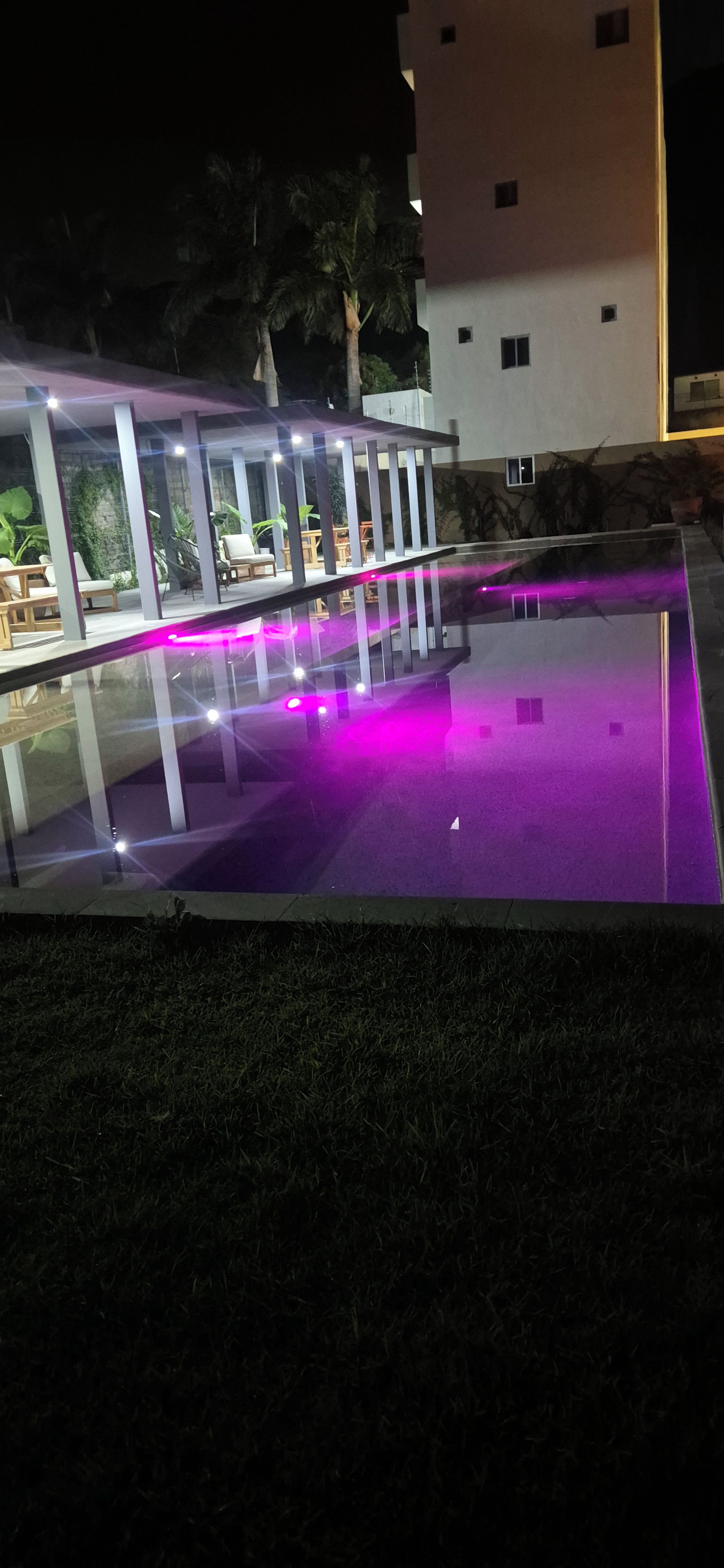 Un espace piscine délimité par une paroi en verre, avec un bâtiment en arrière-plan.