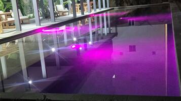 Un espace piscine délimité par une paroi en verre, avec un bâtiment en arrière-plan.