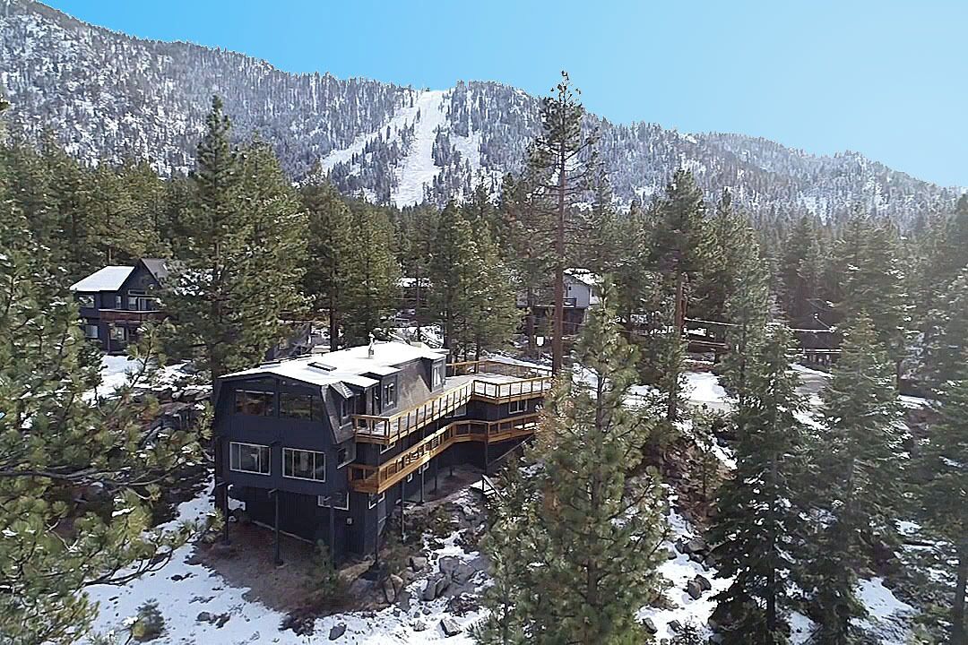 A multi-story lodge with a balcony and a view of a snowy mountain.