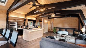 Eine moderne Küche mit Kochinsel, ein Essbereich mit Tisch und Stühlen sowie ein gemütlicher Wohnbereich mit Sofa und Kamin.