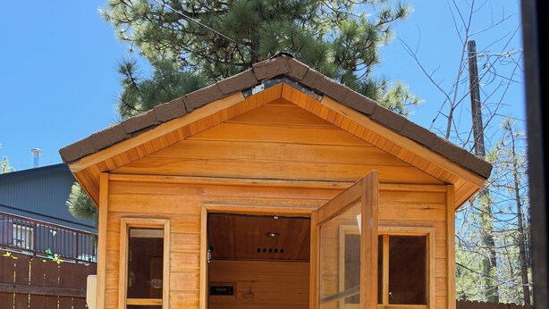 A wooden sauna with a sloped roof, a bench inside, and a door with glass panels. - Tahoe Sanctuary - Mtn Lake Views & AC (South Lake Tahoe)