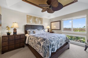 A bedroom with a large bed, two bedside tables with lamps, a ceiling fan, and a window with a view of the outdoors. - 🌴 Hale Kolepa | AC | Located By Mauna Lani Golf Course 🌴 (Waimea)
