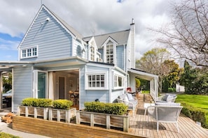 A two-story house with a covered patio area, a chimney, and a lawn. - Fantail Cottage - Greytown (Greytown)