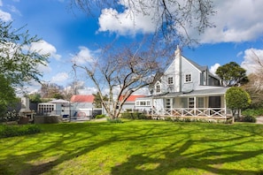 A two-story house with a large front porch and a well-maintained lawn. - Fantail Cottage - Greytown (Greytown)