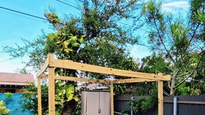A wooden pergola with outdoor furniture, a storage unit, and a fenced garden area. - Miami Oasis (Miami)