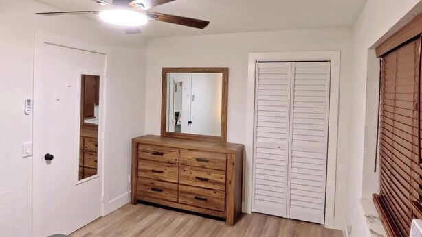 A bedroom with a bed, a wooden dresser, a ceiling fan, and a wardrobe. - Miami Oasis (Miami)
