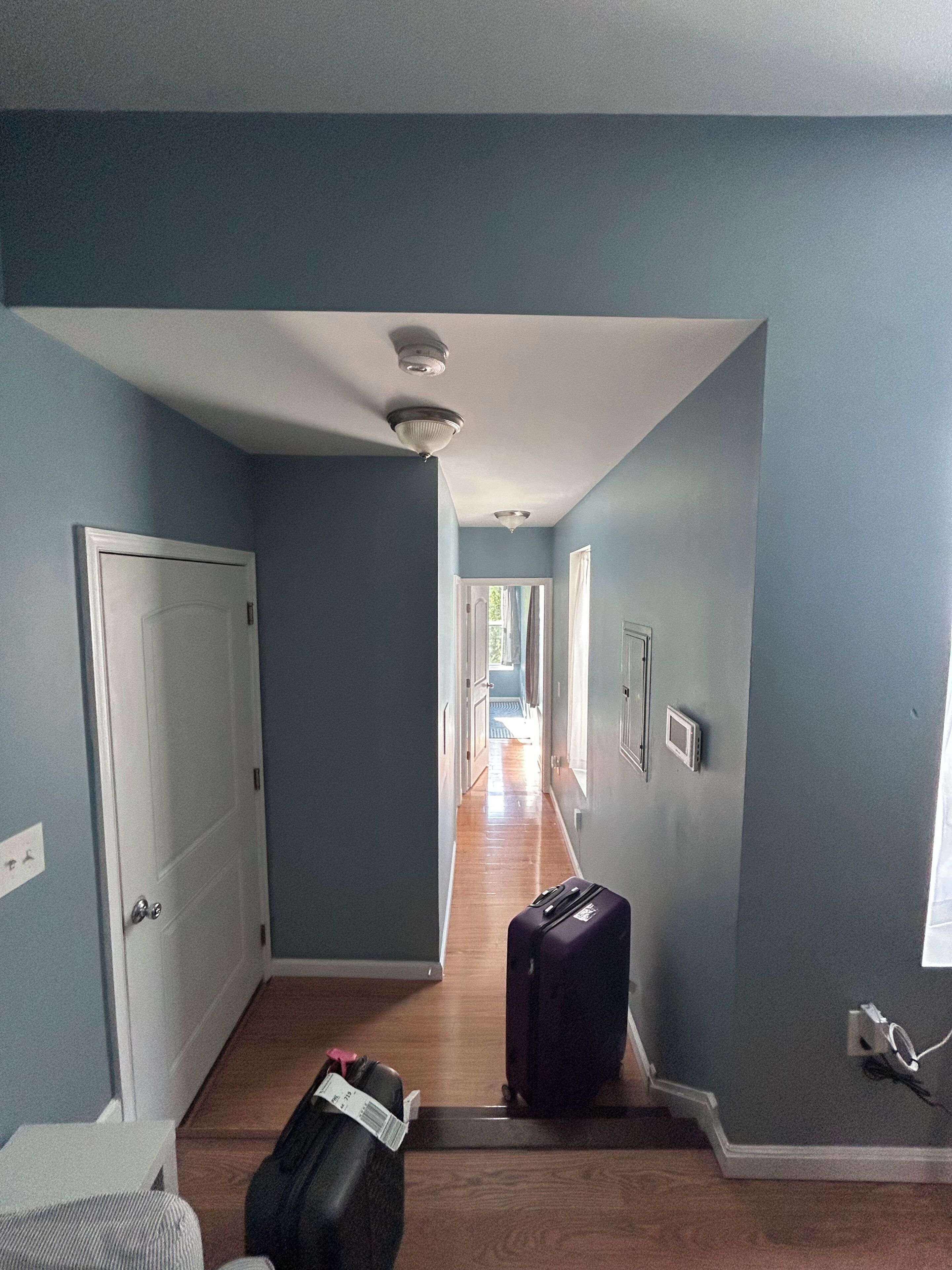 A hallway with a suitcase, a door, and a window.