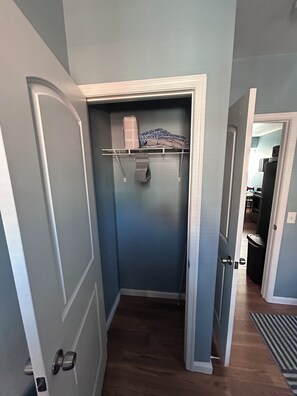 Ein schmaler Flur mit einem Schrank, der gefaltete Kleidung und eine Tasche enthält.