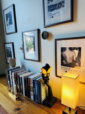 Una estantería con libros, un cuadro enmarcado de un hombre con traje y una lámpara sobre una mesa de madera.