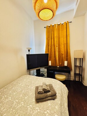 Ein Hotelzimmer mit einem Bett, einem Schreibtisch mit Computer, einem Fernseher und einem Sessel.