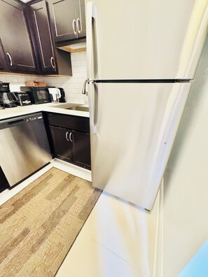 Eine Küche mit Kühlschrank, Mikrowelle, Kaffeemaschine und Geschirrspüler.