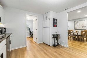 Eine moderne Küche mit weißen Schränken, einem eingebauten Backofen und einem Essbereich mit einem Holztisch und Stühlen.