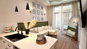 A modern kitchen with a central island, a dining area with a sofa, and a large mirror.