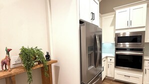 A kitchen with white cabinets, stainless steel appliances, and a wooden countertop with decorative items.