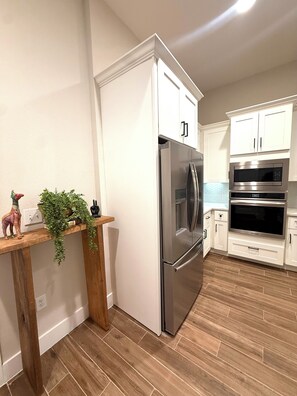 A kitchen with white cabinets, stainless steel appliances, and a wooden countertop with decorative items.