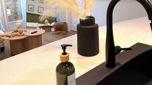 A modern kitchen with a black faucet, a bottle of dish soap, and pampas grass in a vase.