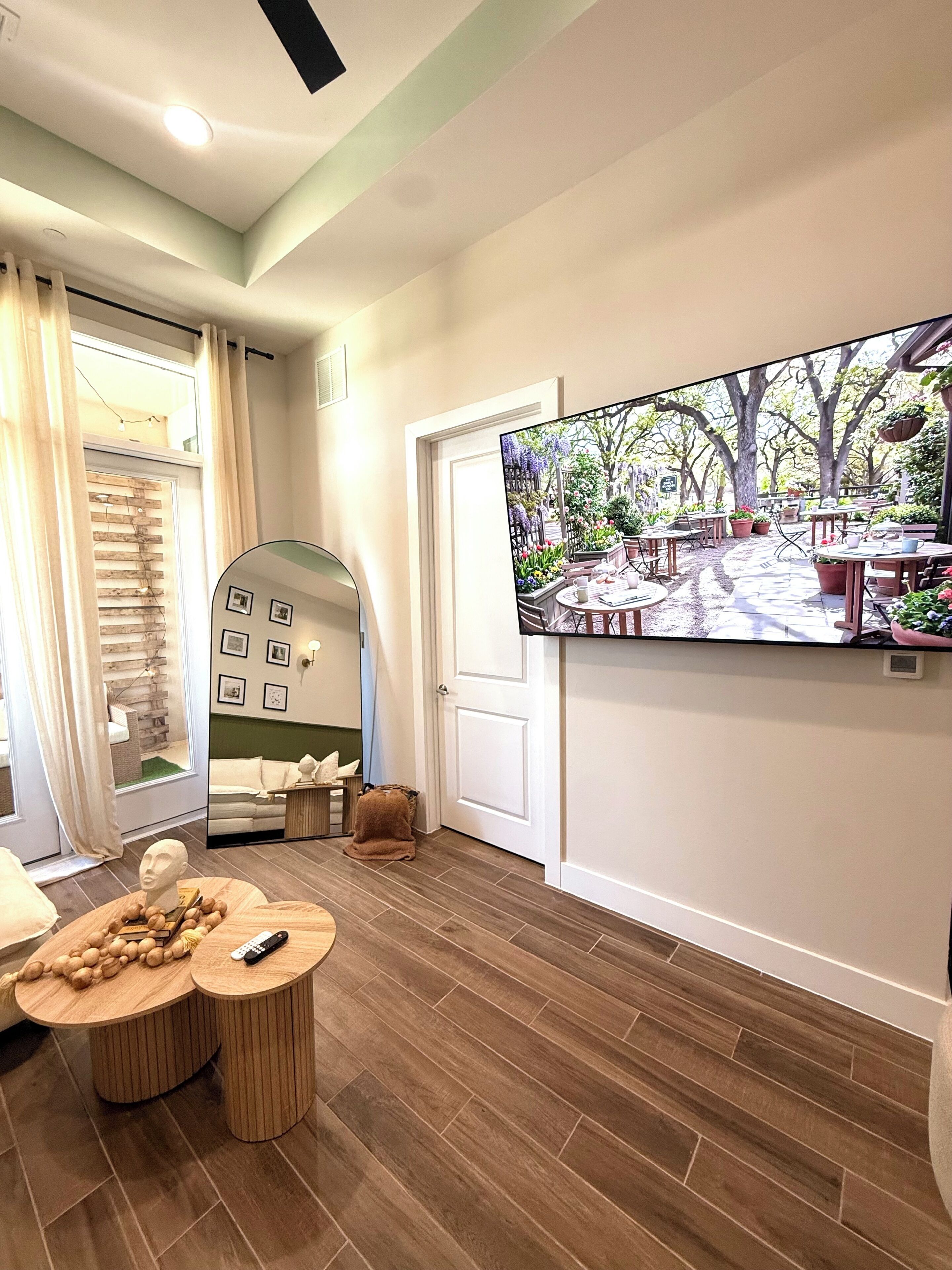 Un salon moderne avec un grand téléviseur, une table basse en bois et un coin salon confortable.