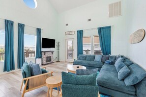 A living room with a sofa, chairs, a TV, and a fireplace. - Bolivar 5BR Beach House - Fenced - Steps to Beach (Bolivar Peninsula)