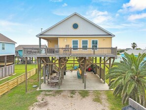 A two-story house with a balcony and a covered patio area. - Bolivar 5BR Beach House - Fenced - Steps to Beach (Bolivar Peninsula)