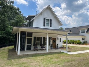 Ein zweistöckiges Haus mit überdachter Veranda und Garage.