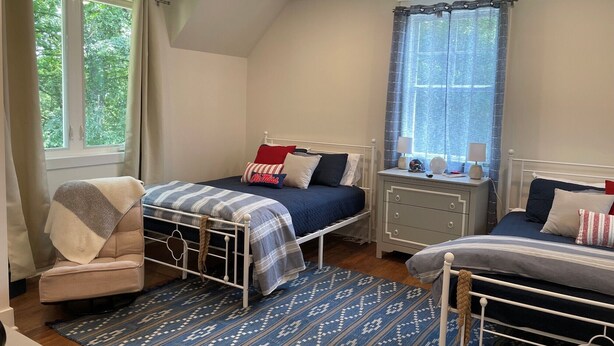 A bedroom with two beds, a chair, a nightstand, and a window with curtains. - 3-Bdrm Oxford Home Away From Home 6 mins to The Square, 3.9 miles to The Stadium (Oxford)