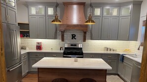 A kitchen with grey cabinets, a central island with stools, a stove, and pendant lighting. - 3-Bdrm Oxford Home Away From Home 6 mins to The Square, 3.9 miles to The Stadium (Oxford)
