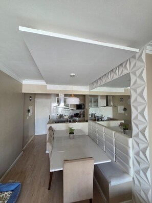 A modern kitchen with a central island, pendant lighting, and a dining area with a bench. - Apartment in Tatuapé, Bragança mountain range, x Itapura (São Paulo)