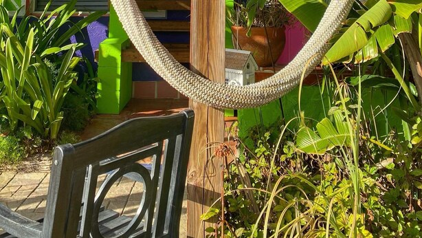 A wooden pergola structure with a sign that reads 'TOES IN THE SAND WINE IN HANDS LIFE IS GOOD.'