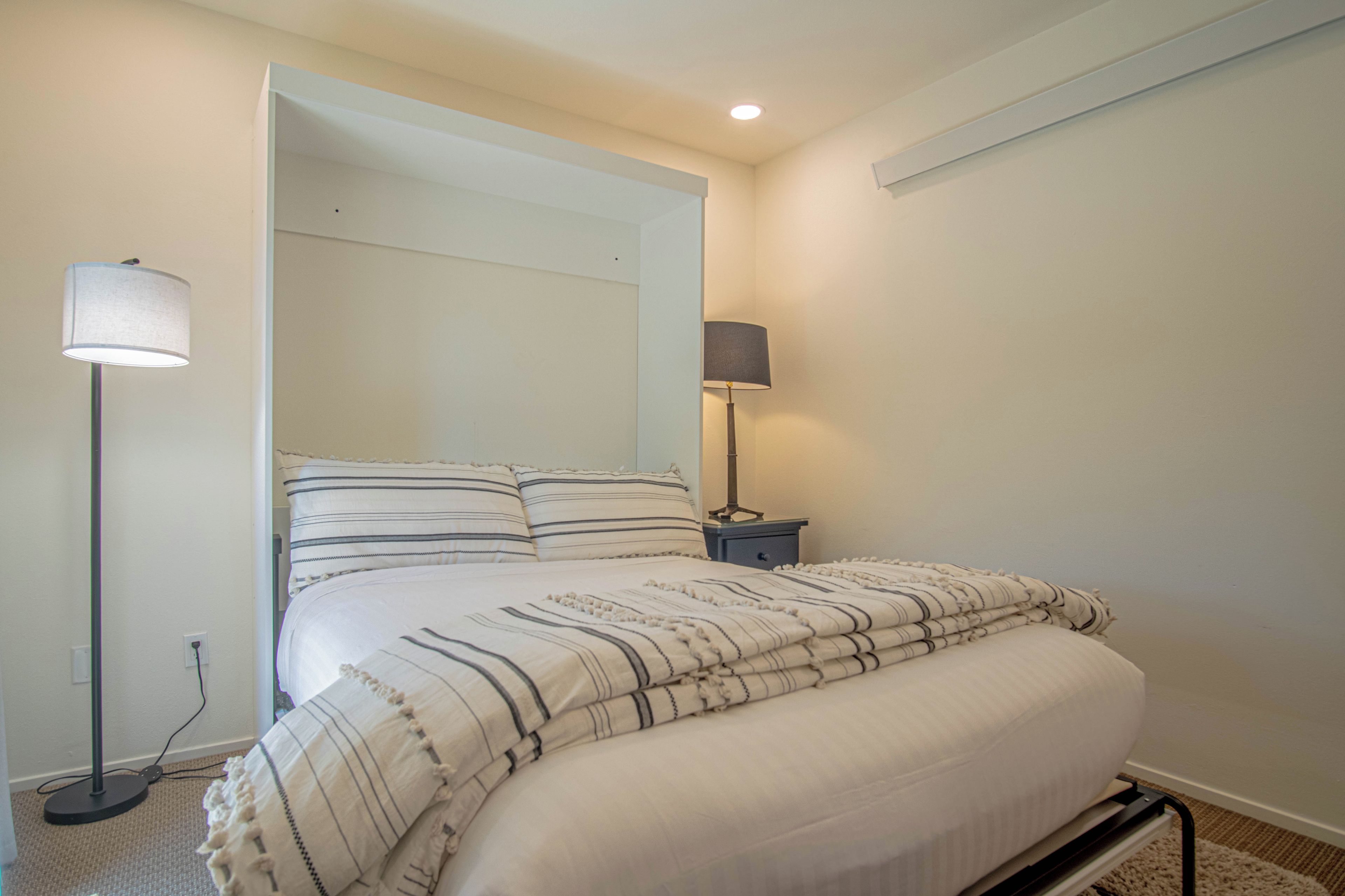 A bedroom with a bed, two bedside lamps, and a nightstand.